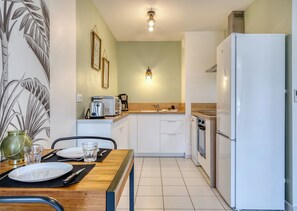 A compact kitchen with white cabinets, a refrigerator, a coffee maker, and a toaster. - XAVIER – F2 cosy avec balcon à Rouen (Rouen)