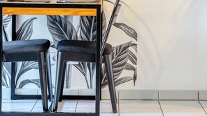 A dining area with a table, two chairs, and a wall with a leaf pattern. - XAVIER – F2 cosy avec balcon à Rouen (Rouen)