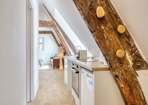 Eine moderne Küche mit einem Holzbalken, einem Essbereich mit einer Couch und Blick auf einen Dachbodenraum.