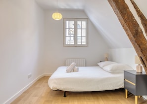A bedroom with a bed, bedside tables, a radiator, and a window. - JACKY - Joli 2 pièces avec vue sur l'Eglise Saint Maclou (Rouen)