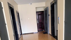Un pasillo con piso de mármol, una puerta de madera oscura y una puerta de ascensor negra.