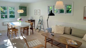 Ein gut beleuchteter Raum mit einem Esstisch, Stühlen, einer Couch und einer Stehlampe.