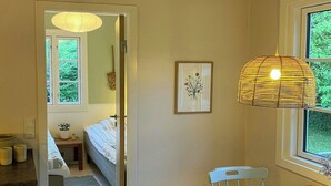 Ein Zimmer mit einem Bett, einem Tisch, einem Stuhl, einer Pendelleuchte und einem Fenster.