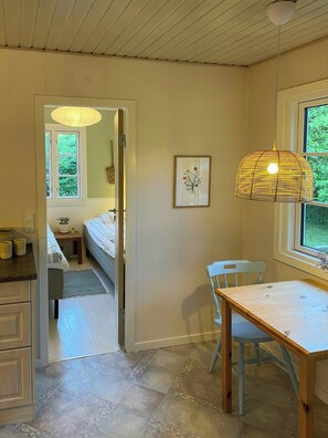A room with a bed, a table, a chair, a hanging light fixture, and a window. - Holiday home with orangery and private garden (Vejby)