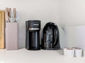 Eine Kaffeemaschine und ein Wasserkocher auf einer Küchenarbeitsplatte.
