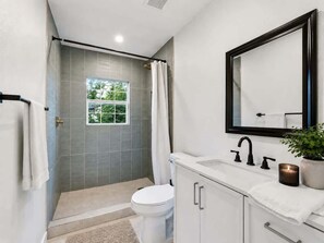 Une salle de bain moderne équipée d’une douche, de toilettes, d’un lavabo et d’un miroir.