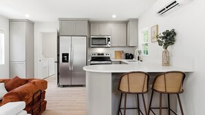 Una cocina moderna con una isla central, taburetes de bar y un refrigerador.
