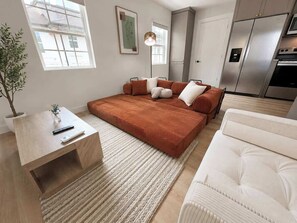 Un salon moderne avec un canapé, une table basse et un fauteuil blanc.