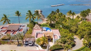 Un complexe hôtelier comprenant plusieurs bâtiments, une piscine et une plage bordée de palmiers.