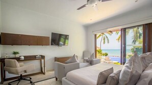 Une chambre à coucher avec un lit, un bureau, une chaise, une télévision et une vue sur l’océan.