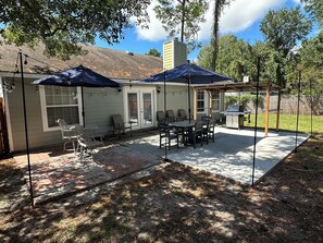 A backyard patio with a grill, outdoor seating, and umbrellas. - Family Retreat Near Kings Bay & St. Marys (Kingsland)