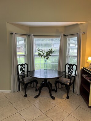 A dining area with a round table, two chairs, a vase with a plant, and a lamp on a side table. - Family Retreat Near Kings Bay & St. Marys (Kingsland)