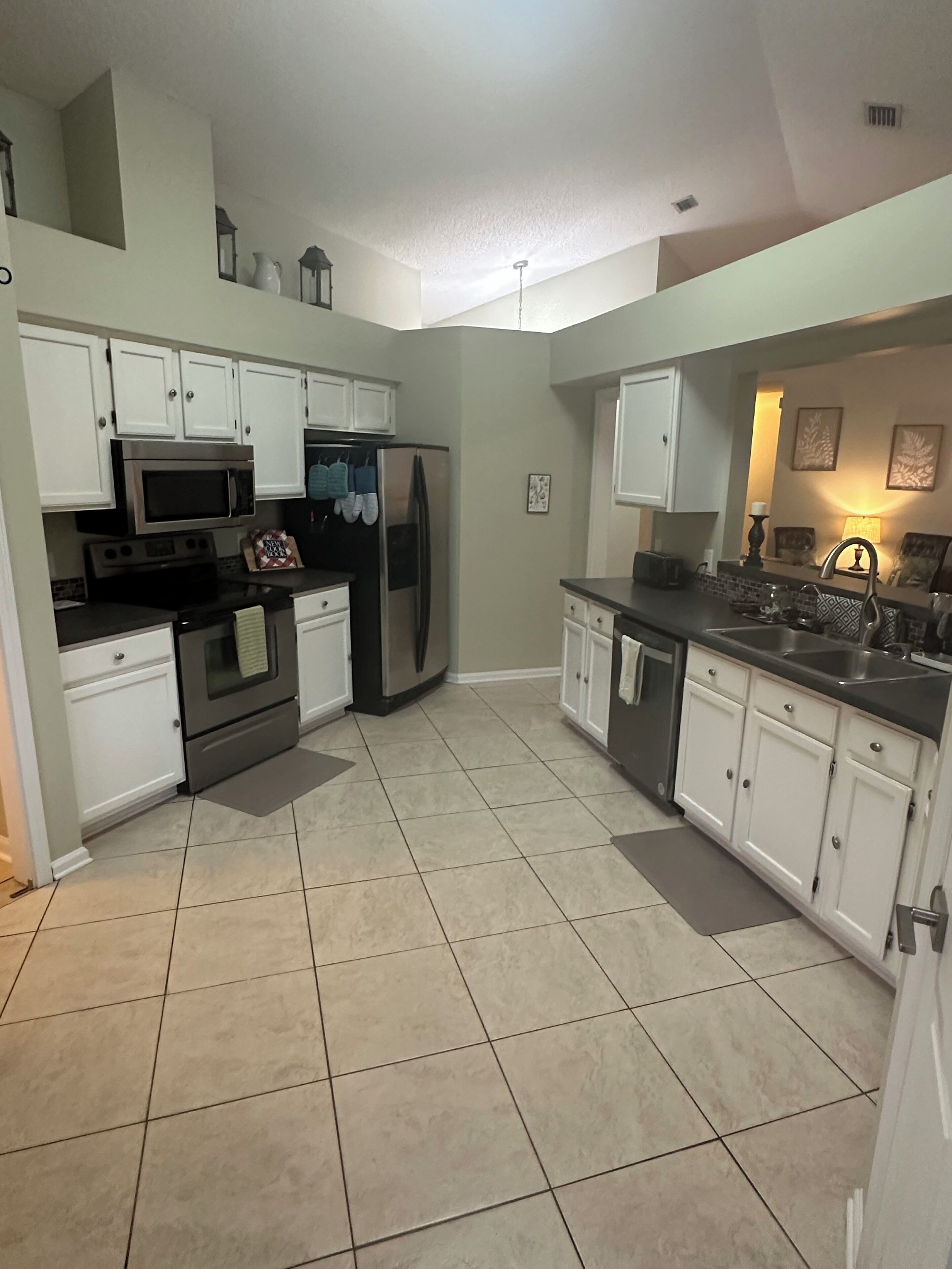A kitchen with white cabinets, stainless steel appliances, and a tiled floor.