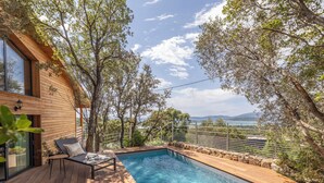 Un pontile di legno con piscina, una sedia a sdraio e vista sul mare.