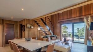 Un interno moderno con zona pranzo, divano, scala e vista attraverso una porta in vetro.