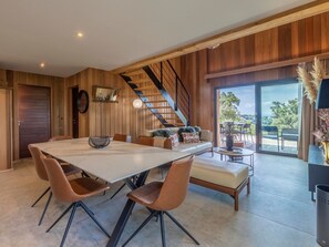 Ein modernes Interieur mit Essbereich, Sofa, Treppe und Blick durch eine Glastür.