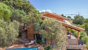 Una villa in legno con piscina, area salotto esterna e garage.
