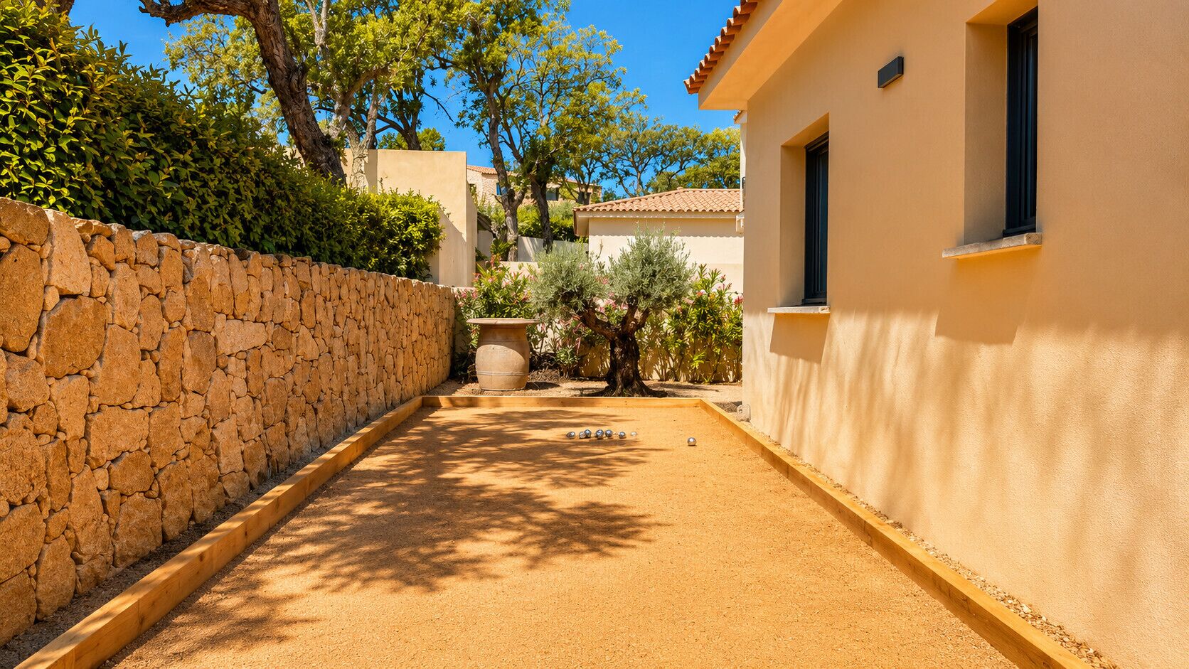 A courtyard with a stone wall, a building with a window, and a garden area.