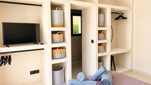 A modern room with a flat-screen TV, storage baskets, and a neatly folded towel. - Casa Isula Di Santa Lucia (Sainte Lucie de Portio Vecchio)