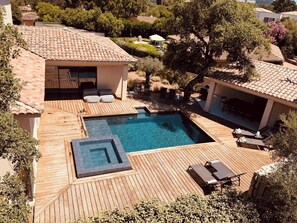 A pool with a wooden deck, lounge chairs, and a small building with a tiled roof. - Casa Isula Di Santa Lucia (Sainte Lucie de Portio Vecchio)