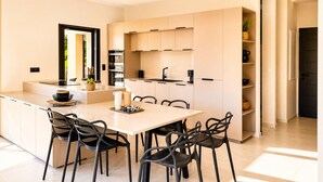 A modern kitchen with a central island, built-in ovens, and a dining area with chairs. - Casa Isula Di Santa Lucia (Sainte Lucie de Portio Vecchio)