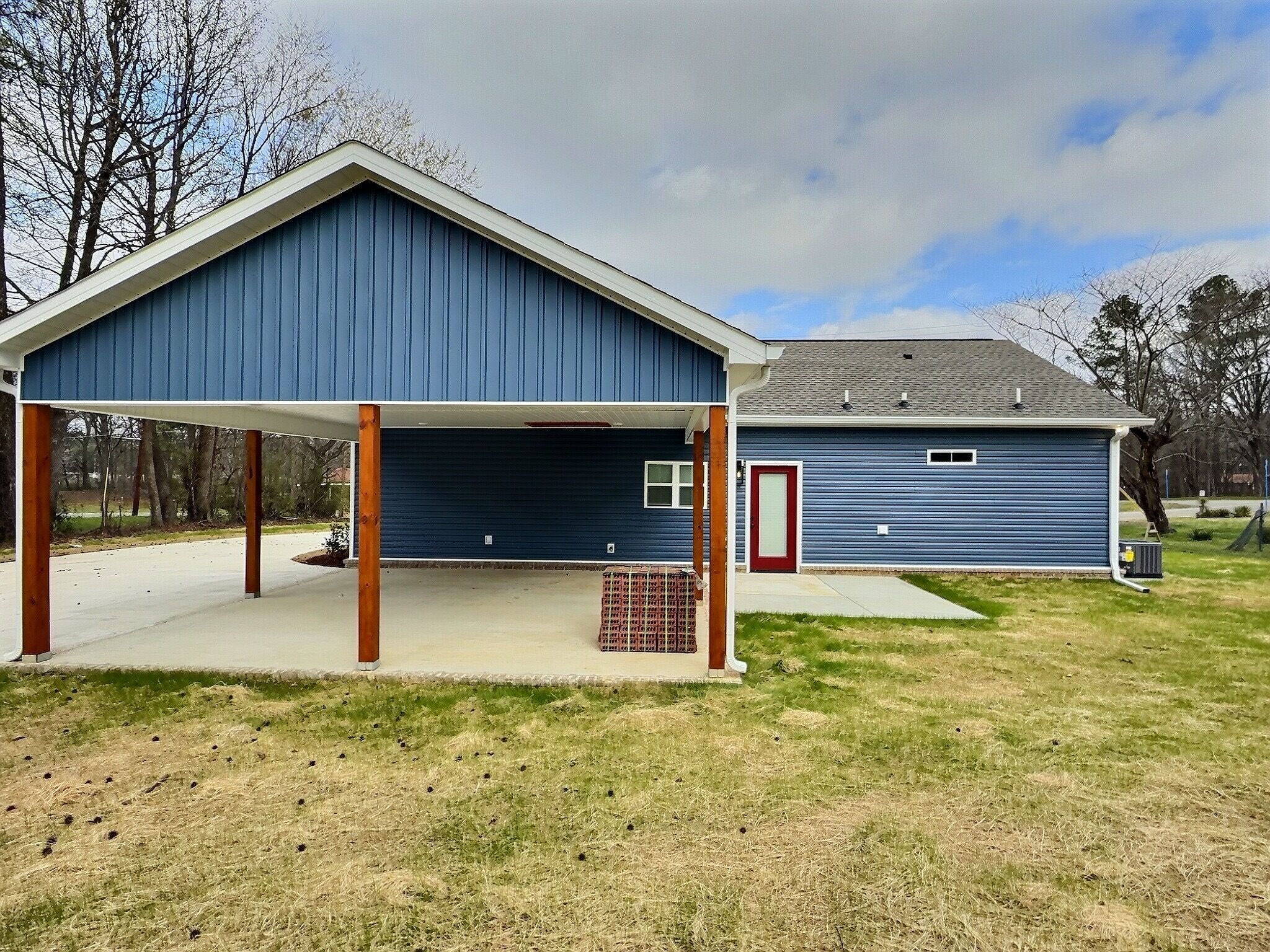 A two-story building with a covered garage and a red door.