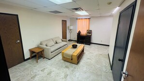 A room with a sofa, a small table, a wooden bench, a desk, and a chair.