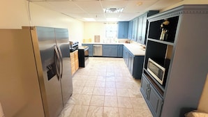 A kitchen with a refrigerator, dishwasher, microwave, and cabinets.