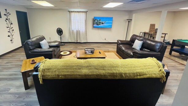 A living room with two leather sofas, a coffee table, a TV, and a pool table.