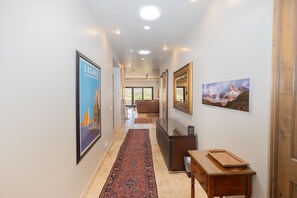 A hallway with a patterned rug, framed artwork, and a wooden side table. - Desert Retreat w/ Red Rock Views & Private Casita (St. George)