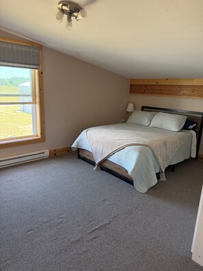 A bedroom with a bed, a window, and a ceiling fan.