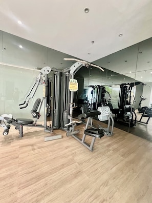 Ein Fitnessraum mit verschiedenen Trainingsgeräten, einem Warnschild und einem Holzboden.