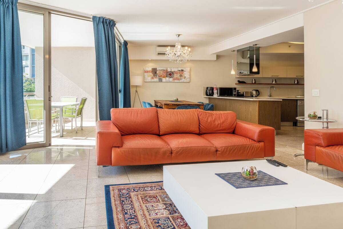 A modern living room with a sofa, coffee table, and a dining area with chairs.