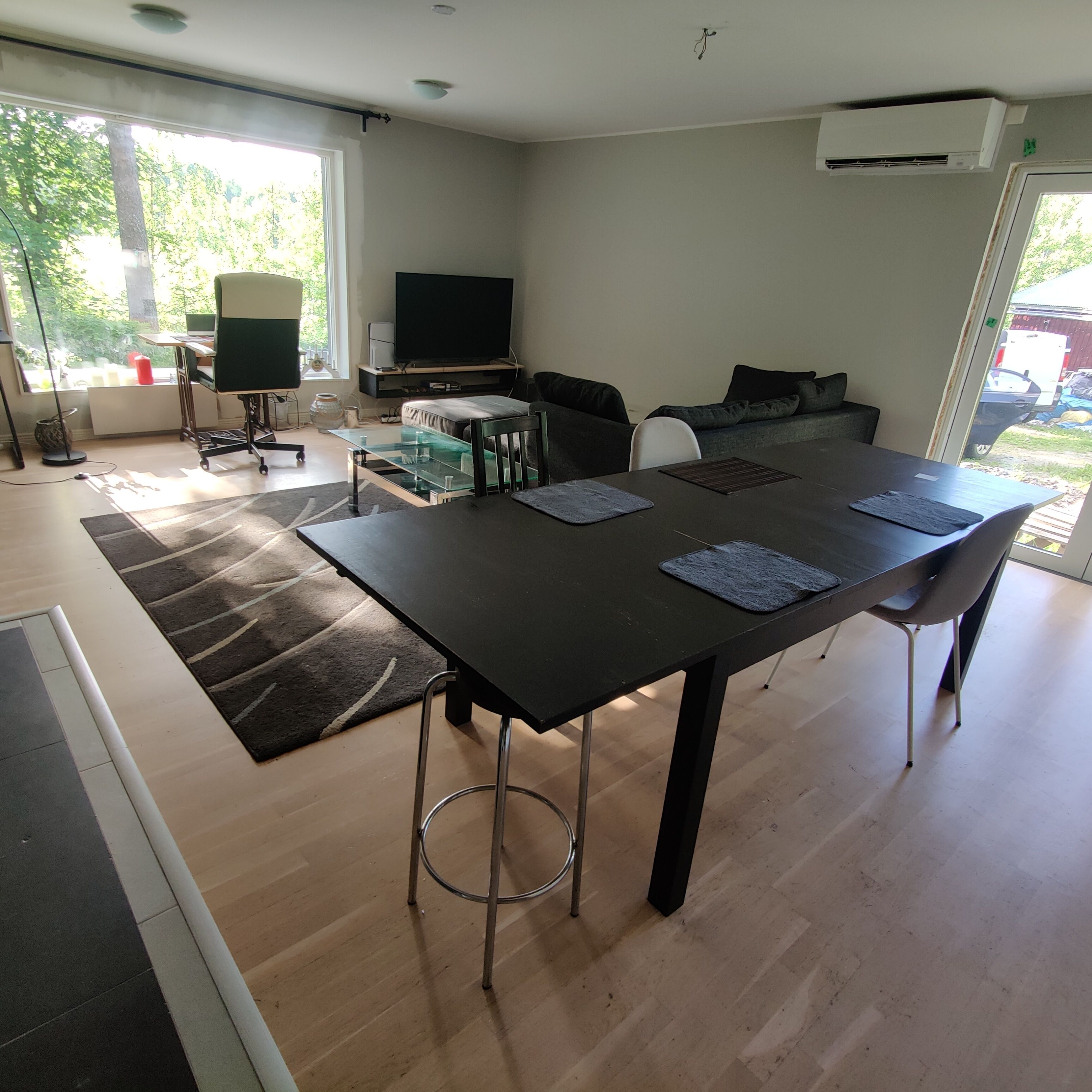 Una sala de estar moderna con una mesa grande de color oscuro, un televisor de pantalla plana y un sofá.