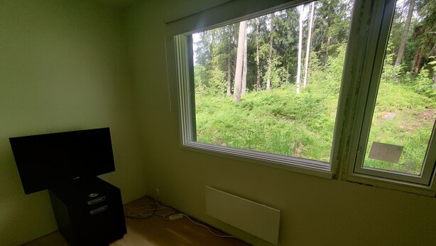 A room with a large window, a radiator, a black cabinet, and a black rug.