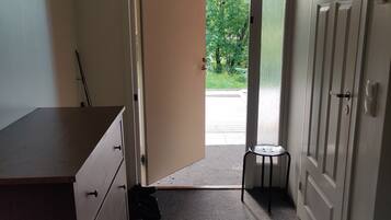 Un pasillo con una puerta que da al exterior, un taburete pequeño y un escritorio con cajones.