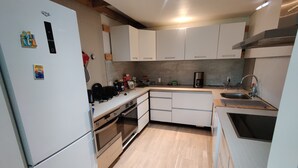 A compact kitchen with white cabinets, a built-in oven, a sink, and a coffee maker.