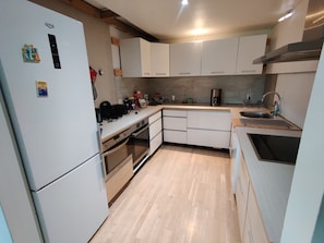 A compact kitchen with white cabinets, a built-in oven, a sink, and a coffee maker.