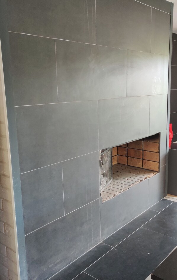 A tiled wall with a recessed fireplace area.