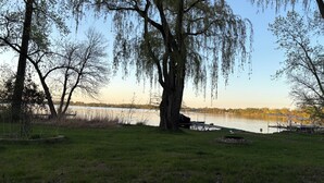 A lakeside park with trees, a dock, and a grassy area.