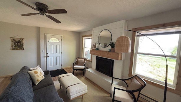 A living room with a fireplace, a ceiling fan, a sofa, and a chair.