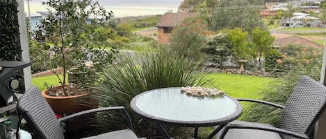 Une terrasse avec des chaises en osier, une table ronde et une plante en pot.