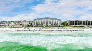 Een hotel aan het strand met meerdere verdiepingen, een strand op de voorgrond en een heldere lucht.