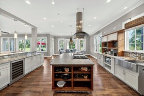 A spacious kitchen with a central island, built-in cabinets, and a large window providing a view of the outdoors. - AMAZING Marsh-view Kiawah Island home with 5 BDs, private pool! (Kiawah Island)