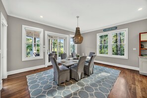 A dining area with a table set for four, surrounded by chairs, a patterned rug, and a chandelier. - AMAZING Marsh-view Kiawah Island home with 5 BDs, private pool! (Kiawah Island)