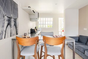 Eine moderne Küche mit Essbereich, einem grauen Sofa und einem großen Fenster.