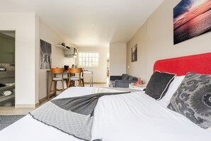 Ein Schlafzimmer mit einem Bett, einem Schreibtisch, einem Sessel, einer Couch und einem Fenster.