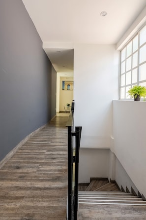 Ein Flur mit Holzboden, einem schwarzen Tisch und einem Blumentopf vor einem Fenster.