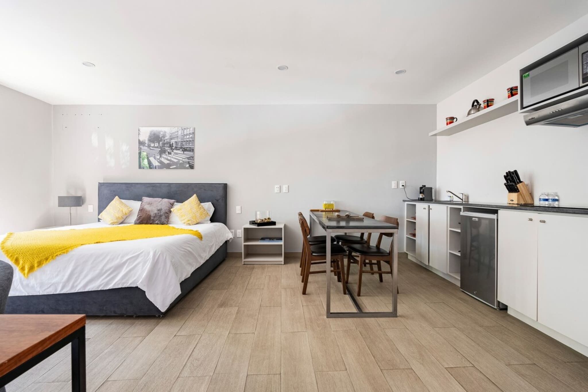 Ein modernes Hotelzimmer mit Bett, Nachttisch und einer Essecke mit Tisch und Stühlen.