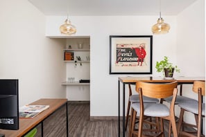 Ein moderner Essbereich mit Holztisch und -stühlen, einem gerahmten Kunstwerk an der Wand und einem Regal mit Gläsern.